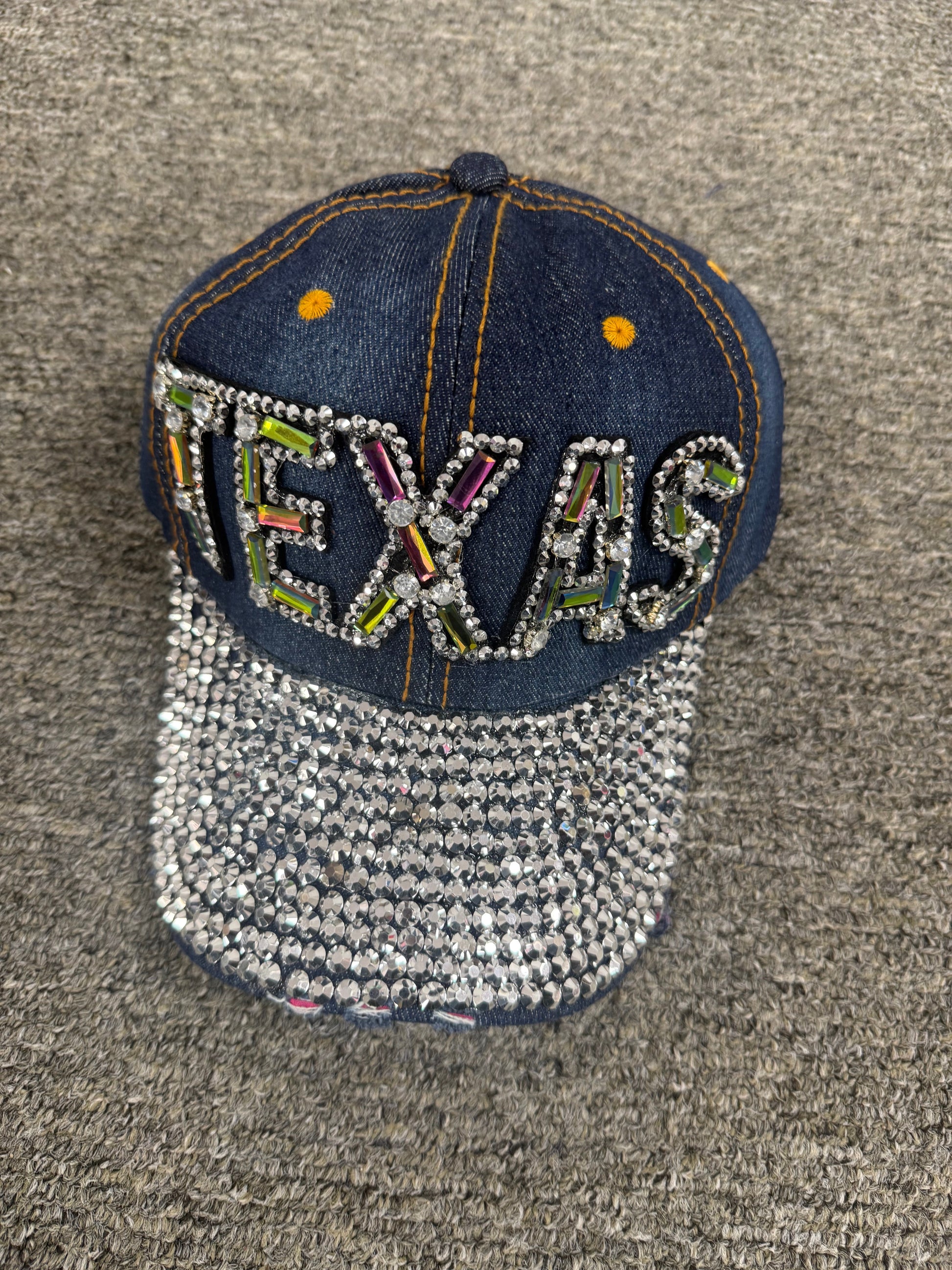 Decorative patch with 'TEXAS' text and rhinestone embellishments on a textured surface
