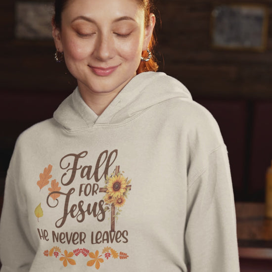 "Fall for Jesus He Never Leaves" hoodie in soft, premium fabric with elegant script design, available in various colors and sizes. Perfect for cozy fall days.