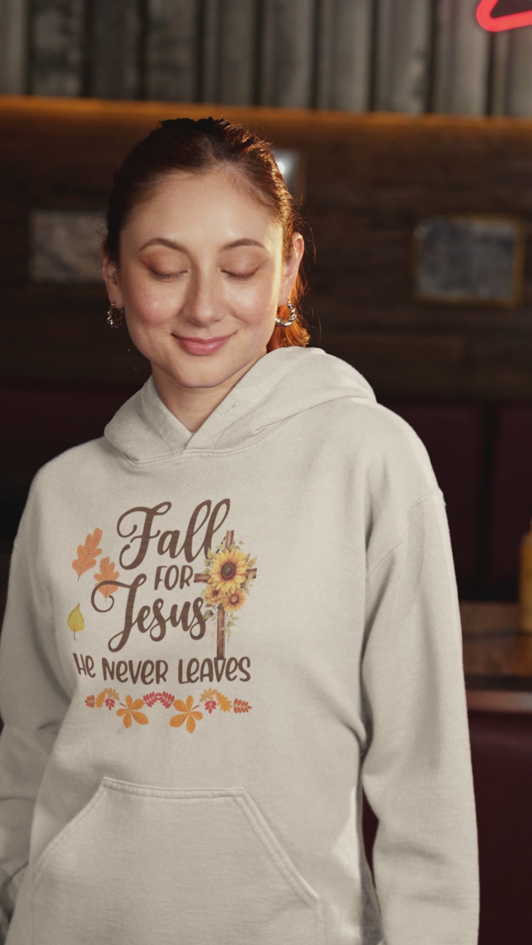 "Fall for Jesus He Never Leaves" hoodie in soft, premium fabric with elegant script design, available in various colors and sizes. Perfect for cozy fall days.